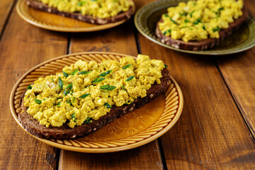 Close up of a plate with bright yellow vegan egg salad sandwiches