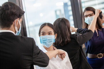 Social distancing. young business handshake meeting in the office and greet bumping elbows, woman coworkers in facial covers protect from COVID-19 coronavirus in office, healthcare concept