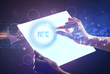 Hand holdig futuristic tablet with NFC inscription, modern technology concept