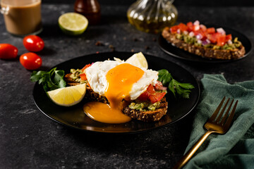 Healthy sandwich with open poached egg on black background