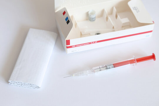 Used dose of Interferon injectable solution in pre-filled syringe for the treatment of Hepatitis C, next to the medicine's leaflet and carton box. Text translation: '180 micrograms'