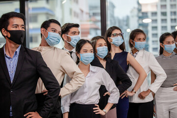 Young people with face masks at work in office. Group of bussiness with face masks looking at camera, corona virus concept.