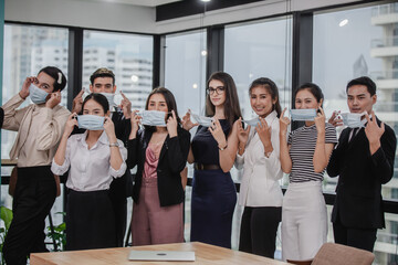 Young people with face masks at work in office. Group of bussiness with face masks looking at camera, corona virus concept.