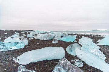 view of glacier debris on a black beach on a cloudy day