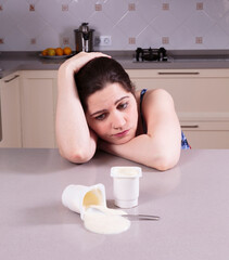 Obraz na płótnie Canvas Depressed young woman looking at a yoghurt spilt