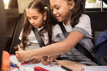 Little girls having fun painting in the back seat of the car. Concept of school transport.