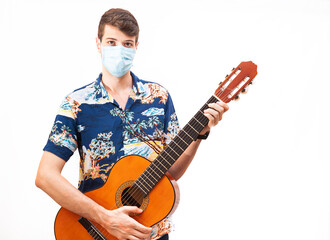 Young guy in a medical mask plays the guitar. Home entertainment in isolation.