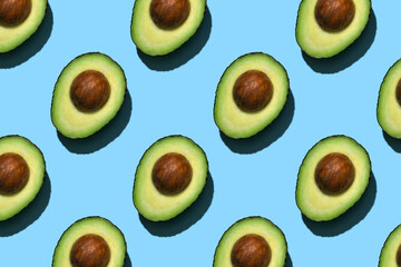 Avocado pattern on blue background. Half avocado background with seed.