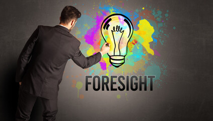 businessman drawing colorful light bulb with FORESIGHT inscription on textured concrete wall, new business idea concept