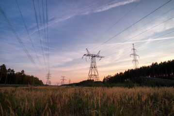 Power line supports at the evening sunset. Electricity pylons at orange sunset.