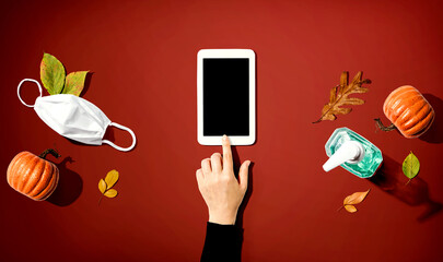 Tablet computer with a mask and a sanitizer bottle in Autumn