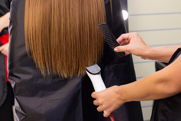 Naklejka premium Hairdresser with a hair machine. cutting off split ends of hair with a clipper. close up.