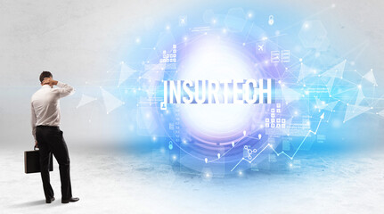 Rear view of a businessman standing in front of INSURTECH inscription, modern technology concept