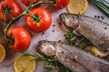 fresh rainbow fish trout on black stone background with vegetables 