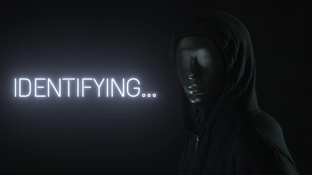 Man wearing black mask and the light revealing IDENTIFYING word