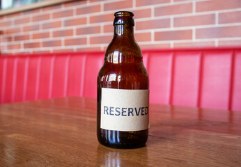A glass bottle on a wooden table in a restaurant with the inscription Reserved