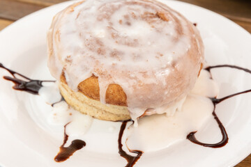 Cinnamon bun dripping with warm icing is considered a dessert or breakfast as a delicious meal.