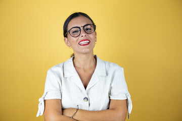 Beautiful woman over yellow background crossed arms looking at the camera smiling