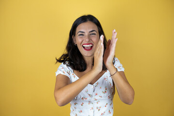Beautiful woman over yellow background clapping and applauding happy and joyful, smiling proud...