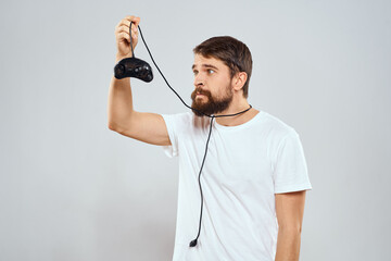 A man with a gamepad in his hands playing games leisure lifestyle technology white t-shirt light background