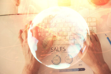 Double exposure of man's hands typing over computer keyboard and business theme hologram drawing. Top view. Financial markets concept.