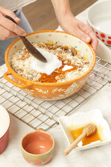 Woman making homemade granola in the kitchen. Serie of photos of all recipe's steps. Mixing all ingredients in the big bowl.