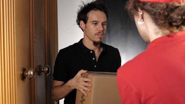 young man opening the door to the woman courier who delivering him a package