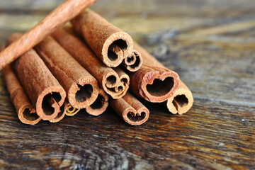 A close up image of several cinnamon sticks on a dark brown table top. 