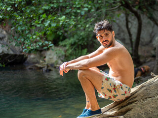 Hombre joven disfrutando del verano en un lago con rocas