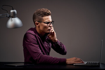 Male manager is sitting at the table and talking on the phone open laptop working office room