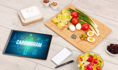CARDIOGRAM concept in tablet with fruits, top view