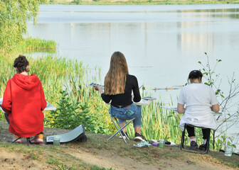 Art school in nature. Artists draw pictures on easels. Painting in the open air.