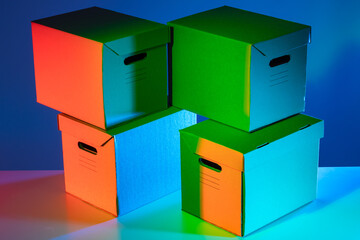 Cardboard boxes with handles in multi-colored lighting. Closed cardboard boxes on blue background. Boxes with handles for transportation.