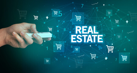hand holding wireless peripheral with REAL ESTATE inscription, online shopping concept