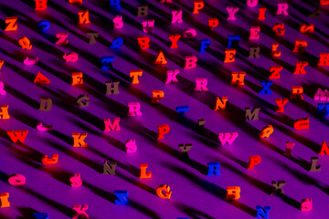 Fototapeta premium Many letters of the Latin alphabet. English letters on the table are illuminated from the side. Latin letters are placed in random order. English-language literature. Education in English.