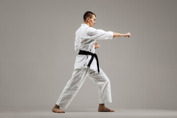 Fototapeta na wymiar man exercising karate, against gray background