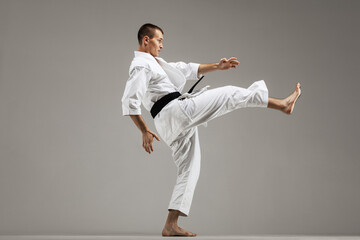 Fototapeta na wymiar man exercising karate, against gray background