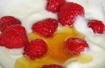 natural yogurt, raspberries and honey in a white cup 