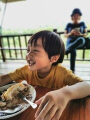 Asian boy eating cream cake.