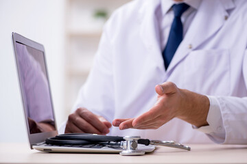 Young male doctor with stethoscope repairing computer