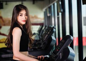 Fototapeta na wymiar Young woman using technology mobile smartphone play music exercise workout on treadmill at fitness gym