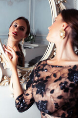 young pretty lady in black lace fashion style dress posing in rich interior of royal hotel room with mirror, luxury lifestyle people concept