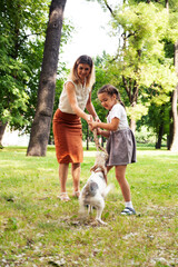 Naklejka na ściany i meble young pretty caucasian mother walking with little cute daughter and dog fox terrier, lifestyle people concept