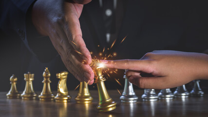 Hand of businessman keeps gold king chess from falling over the attack of opponent with fire sparks light. business partner or collaboration. Business ideas and competition and strategy ideas concept.