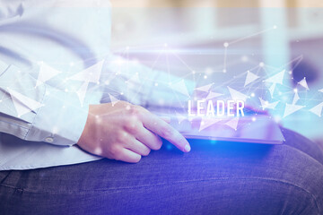 Close up hands using tablet with LEADER inscription, modern business technology concept