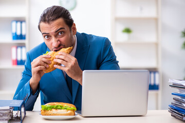 Young male employee having breakfast at workplace