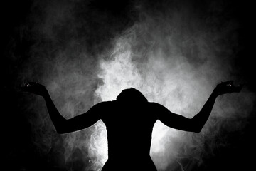 silhouette modern ballet dancer posing on dark background with smoke