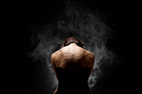 modern ballet dancer posing on dark background with smoke