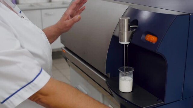 Analysis of milk. Laboratory scientist put measuring cup with liquid on laboratory equipment. milk testing in the laboratory