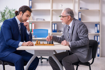 Two businessmen playing chess in the office